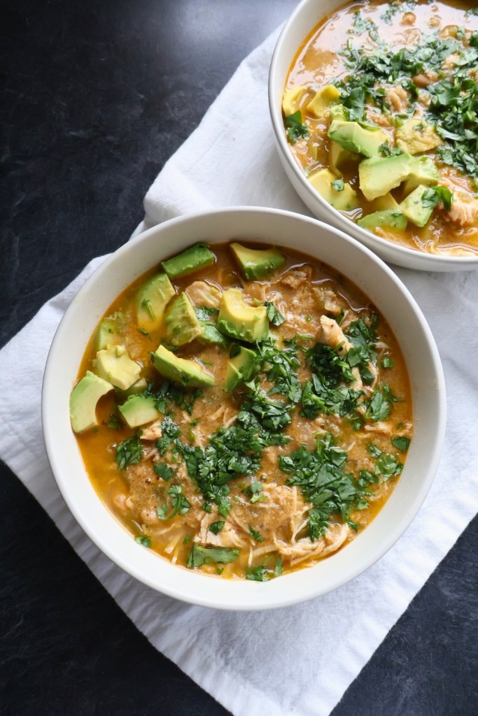 Bowl of creamy Paleo white chicken chili topped with avocado, cilantro, and lime.