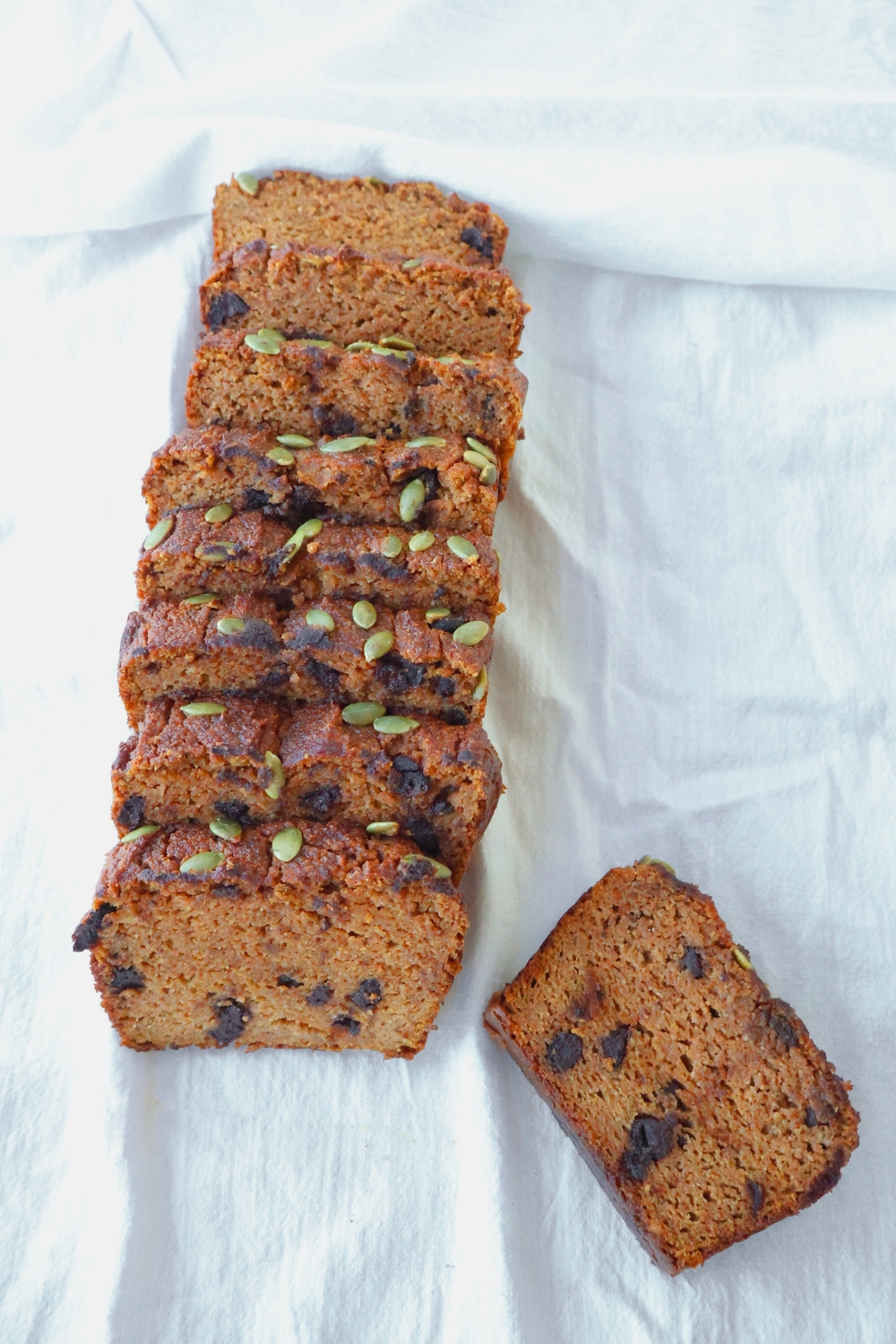 Freshly baked paleo pumpkin bread loaf sliced on a wooden board, gluten free and dairy free.
